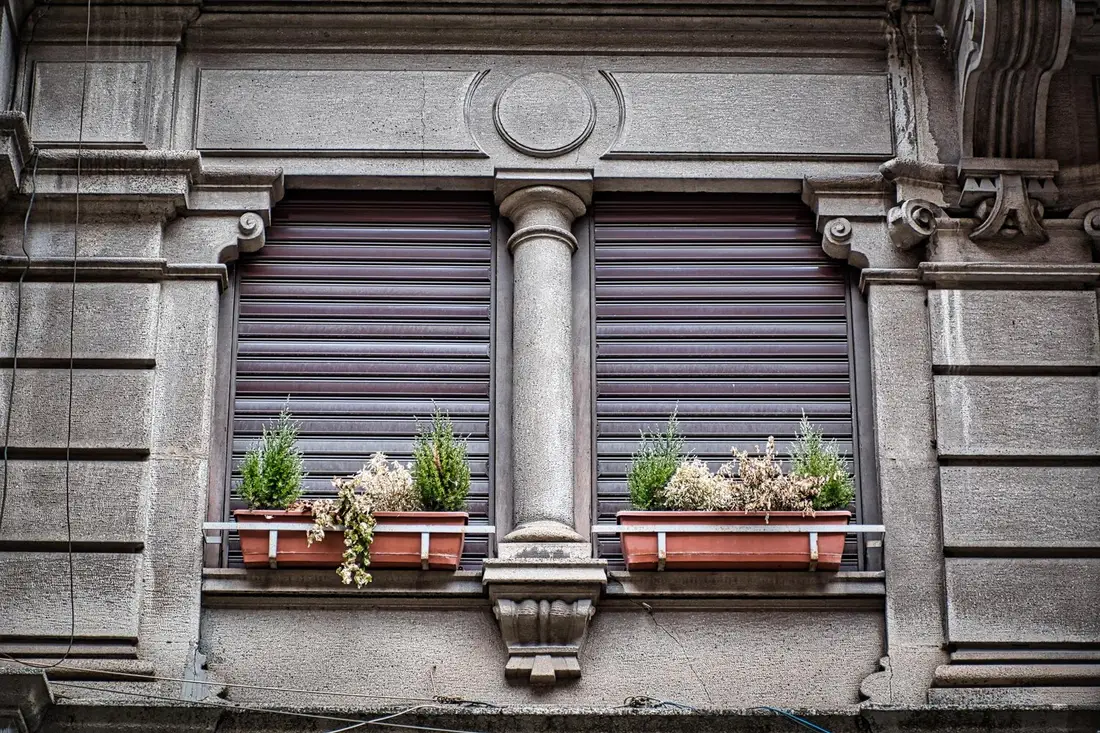 Façade ancienne en pierre de taille avec des volets roulants baissés aux fenêtres